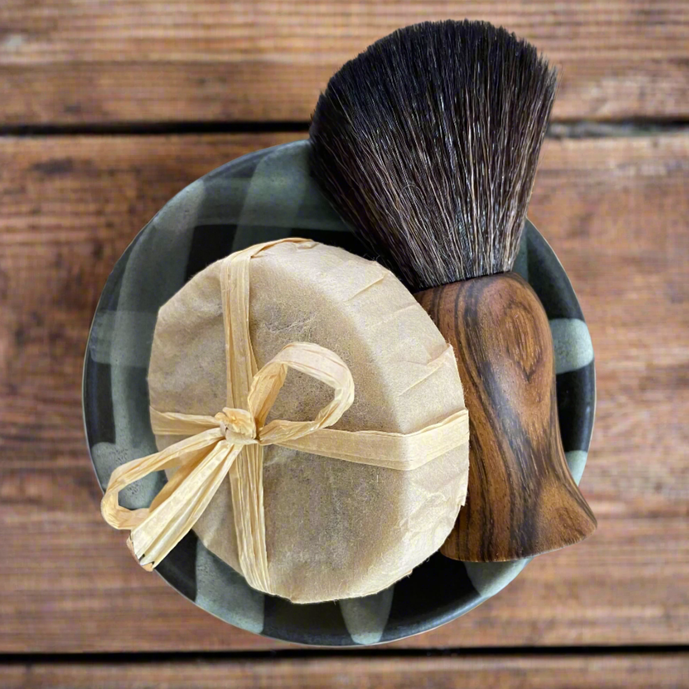 A premium men's wet shave set featuring a ceramic shave bowl, ebony-handled shave brush, and natural shave soap puck – handcrafted by Rogue Raven Grooming.