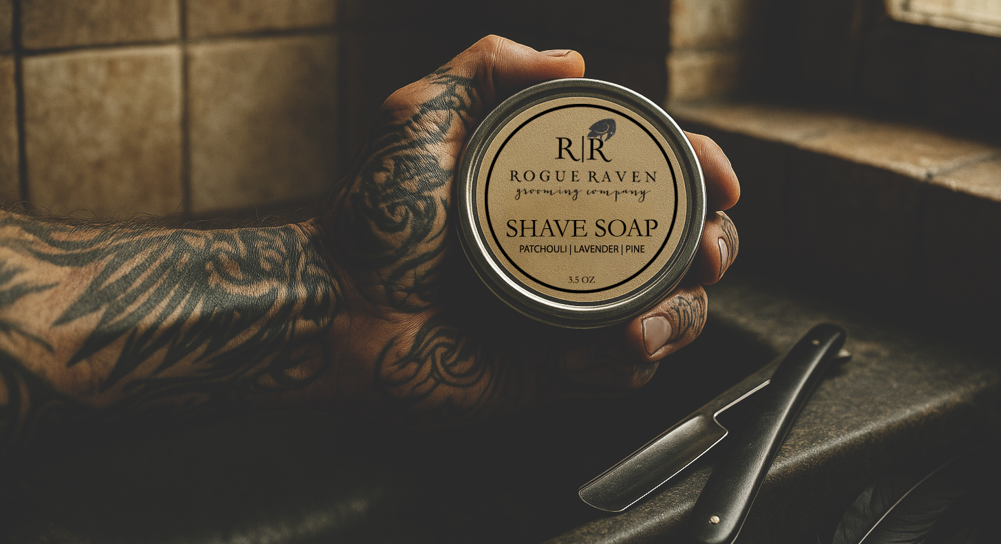 Hand holding a jar of Rogue Raven Shave Soap with a blurred background